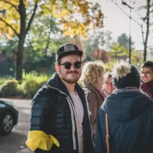 Gruppe unterhält sich, Mann mit gelbem Band am Arm lächelt in die Kamera