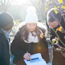 drei winterlich gekleidete Menschen schauen sich die Roadmap an